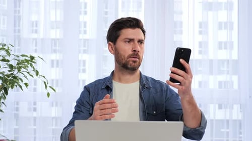 Man Looks Confused While Using Smartphone Indoors
