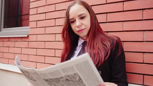 Junge Frau liest Zeitung auf der Straße