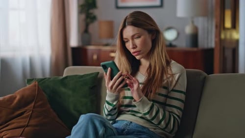 Woman Upset with Phone on Couch Indoors