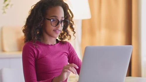 Teenage girl using laptop computer at table indoors