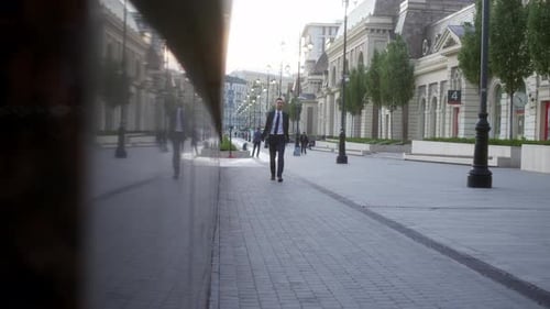 Young Businessman in Strict Blue Suit with Gray Laptop in His Hands Walk Down Street Early in