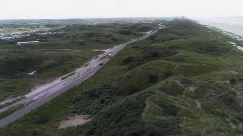 Drone Over Coastal Road and Green Dunes