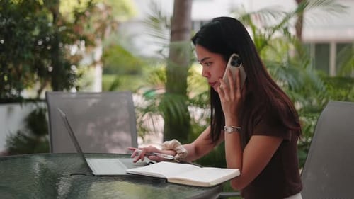 Woman Works on Laptop and Talks on Phone Outdoors