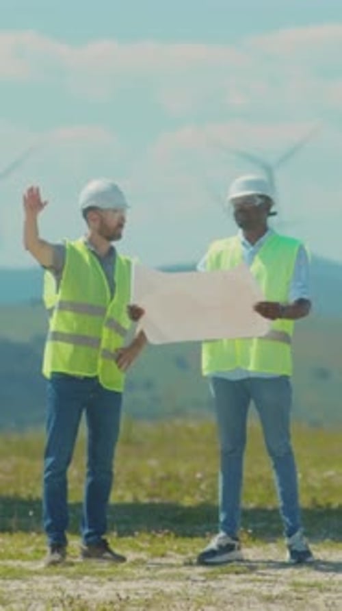Engineers Examine Plans Engineers and Surveyors Collaboratively Assess Wind Farm Design in Open