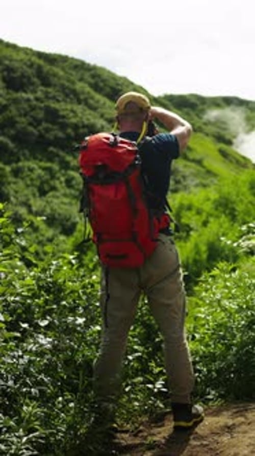 Solo Hiker with Bright Red Backpack Exploring Lush Green Mountain Trail Pausing to Admire Misty