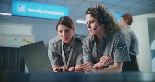 Airport Security Checkpoint Two Female Security Officers in Headset Using Laptop Computer Talking
