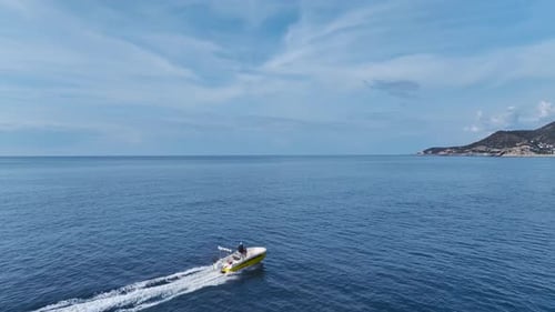 Aerial Video of a Motorboat Speeding Toward the Port Across the Deep Blue Sea Under a Clear Blue Sky