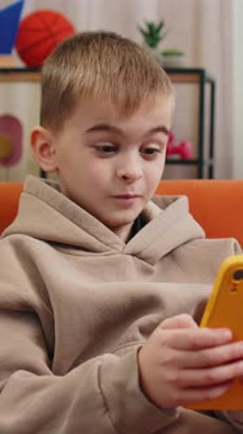 Blond Haired Boy Watches Mobile Phone Indoors