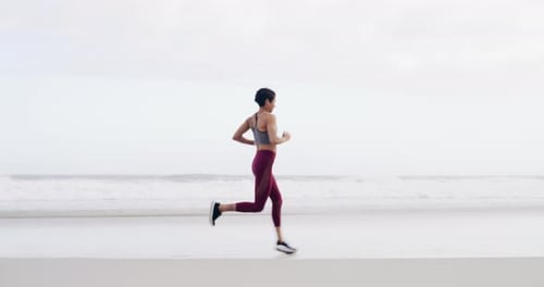 4k video footage of an attractive young sportswoman running on the beach