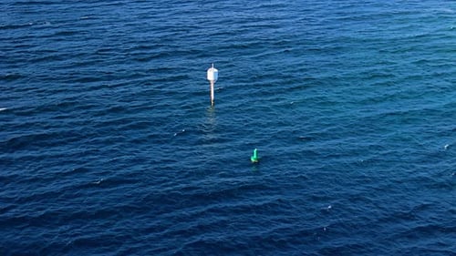 Une grande bouée blanche flotte au milieu de l'eau bleu profond de l'océan avec des bonnets blancs