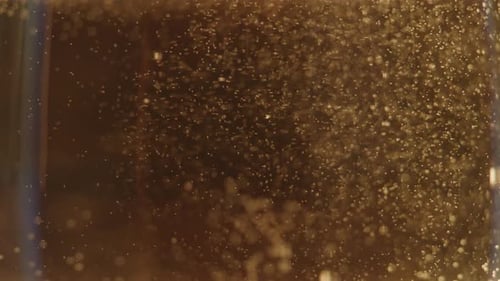 Golden Air Bubbles Floating Slowly in Glass