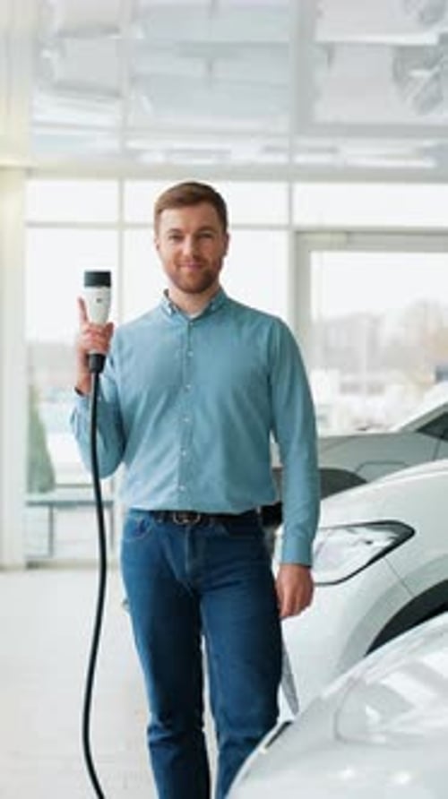 Enthusiastic Man Holding EV Charger Near Car