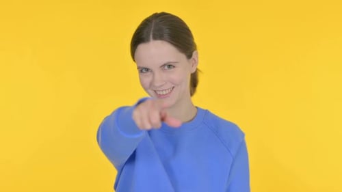 Young Woman Points Forward on Yellow Background