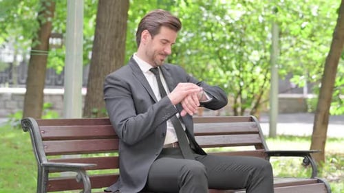 Businessman Waiting, Checking Watch on Park Bench