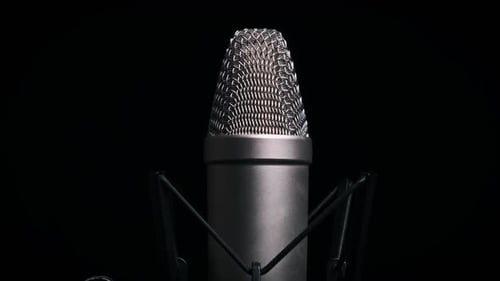 Das Studio-Kondensatormikrofon dreht sich auf schwarzem Hintergrund (Nahaufnahme)