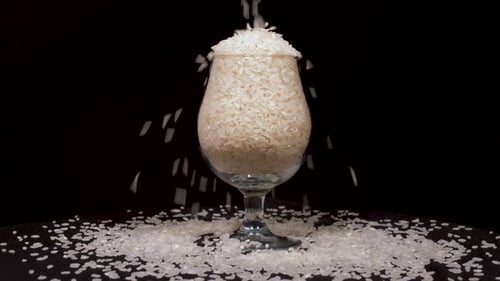 Rice Being Poured Into Stemmed Glass on Black