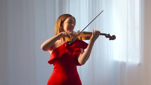 Woman in Red Dress Playing Violin Indoors