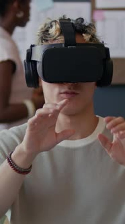 Vertikale Darstellung eines männlichen UX-Designers mit VR-Headset beim Testen des App-Prototyps im Büro
