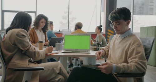Man and Woman Colleagues Talking and Looking at Green Chroma Key Laptop Screen in Office