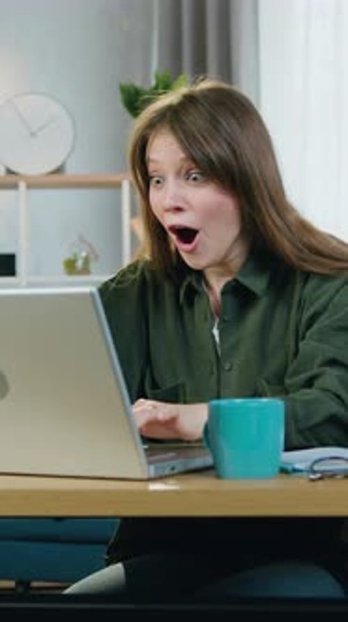 Woman Celebrates Success Using Laptop at Desk