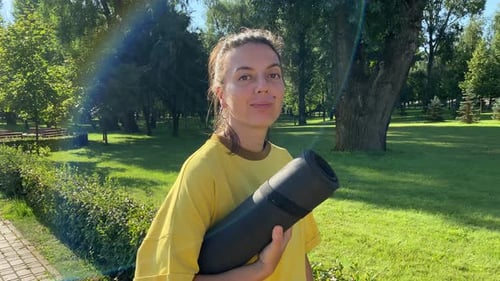 Portrait woman with exercise mat in landscaped picturesque public park
