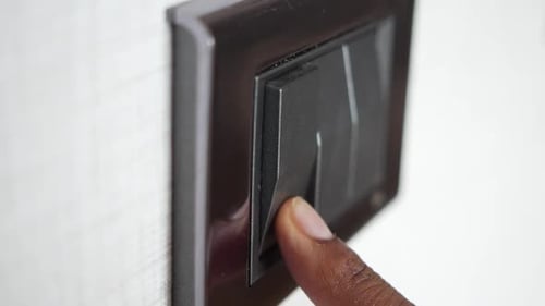 Finger Turns Off Black Light Switch on Wall