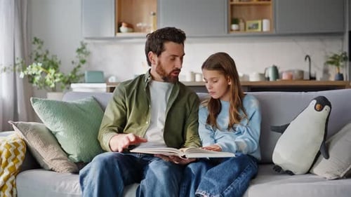 Father and Daughter Reading Book on Cozy Sofa