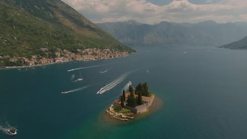 Aerial drone view circling Island of Saint George with multiple boats and yachts passing by in the b