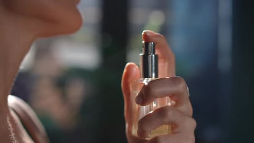 Woman Sprays Perfume onto Neck in Close Up