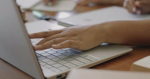 Closeup of Female Hands Typing with Laptop Keyboard and Writing Information in Copybook Studying at