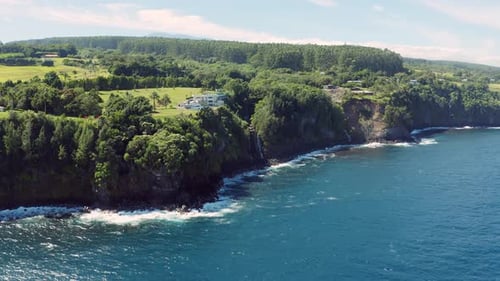 Cinematic surreal Aerial drone shot of a luxurious villa on the edge of a cliff with green foliage s