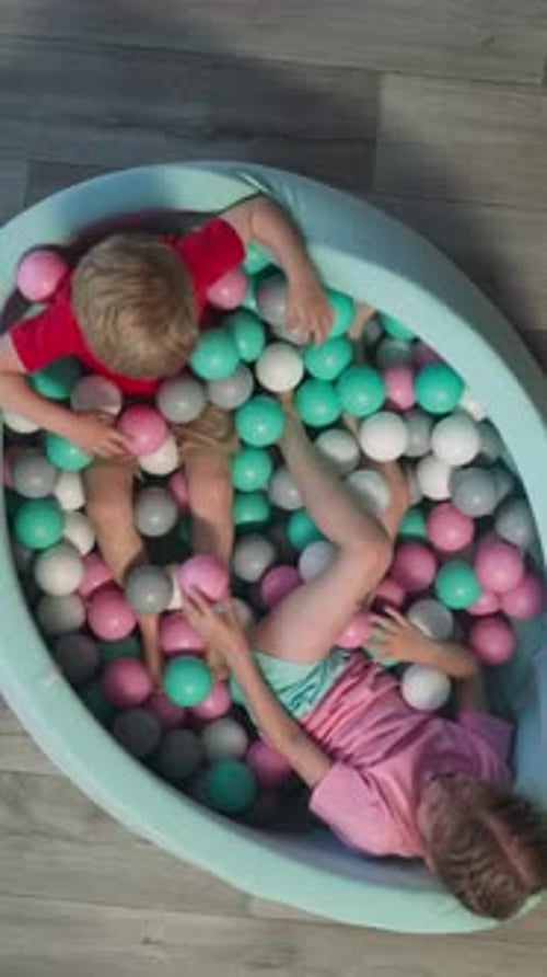 Un tout-petit et un enfant d'âge préscolaire jouent joyeusement allongés dans une piscine sèche
