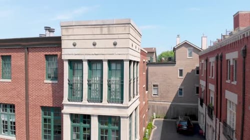 Wide aerial shot of a row of brick and concrete buildings with flat roofs, captured as a drone