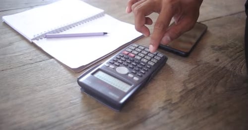 Businessan's hands using calculator and Financial data analyzing on wooden desk at the office