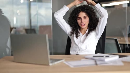 Happy Businesswoman Relaxes in Office Chair After Completing Work on Laptop