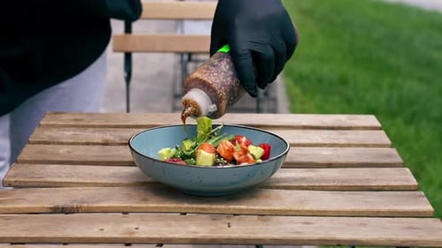 Close Up in a Restaurant on the Street on Plank Table a Blue Vertical Video Plate with a Warm Salad