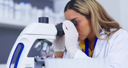 Woman Scientist Viewing Sample Through Microscope in Lab