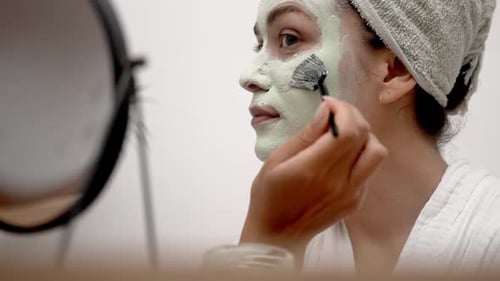Young Woman Applying a Facial Mask in Bathroom