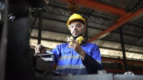 Blue collar workers are working at metal factory.