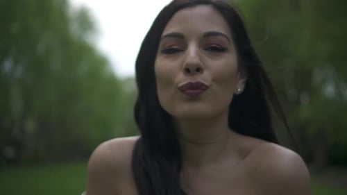 Close up shot of an attractive and carefree brunette latina woman sending kisses to the camera