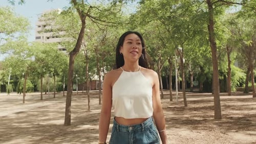 Lovely young woman walks in the city park, looks around