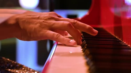 Close-up of an elderly woman playing a red piano