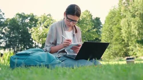 Teenager-Schülerin lernt, ihre Bücher zu lesen, Tablet und Notizbuch, sitzt draußen, zurück zur Schule