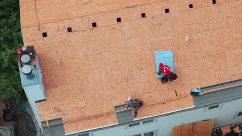 Roofers Installing a New Roof on an Residential Building Aerial Wide Shot View