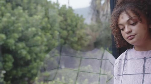 Young Woman Reflecting by Window on Overcast Day