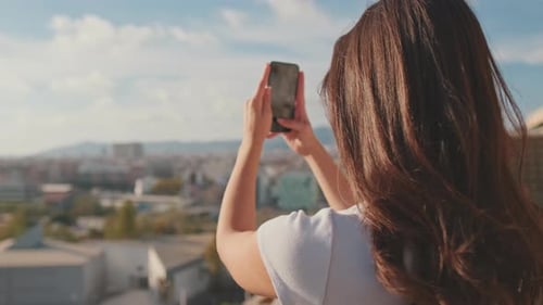 Close up, young woman takes photo on mobile phone while standing on the balcony at home