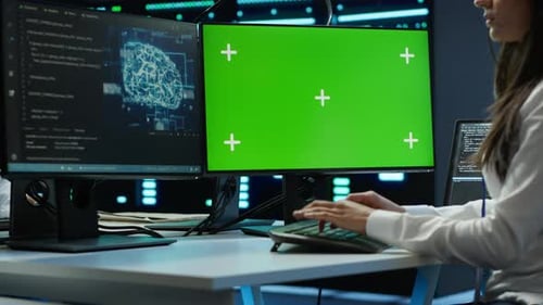Woman works on code with green screen computer