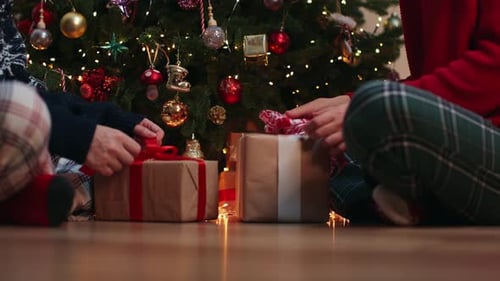 Wrapping Christmas Gifts by Lit Christmas Tree