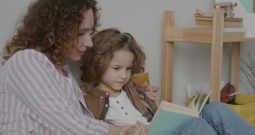 Woman Reading Book with Young Boy at Home