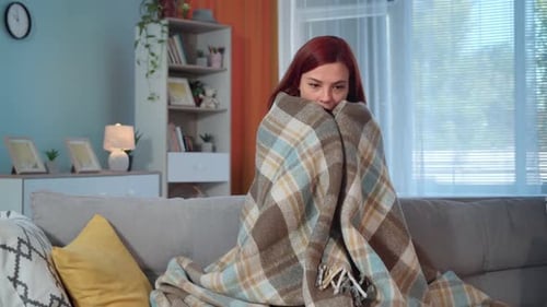 Jeune femme à carreaux est assise sur un canapé dans une chambre froide à la maison